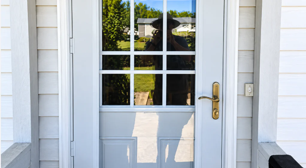 White front door with a divided glass window and a brass handle