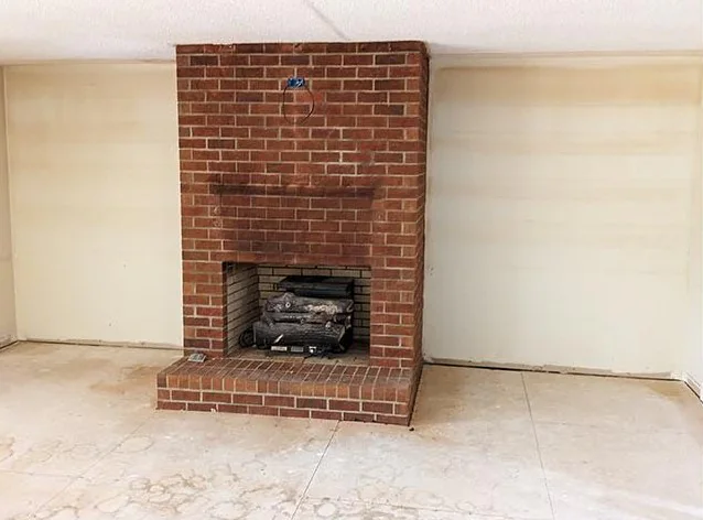 Red brick fireplace in an empty room with a bare floor