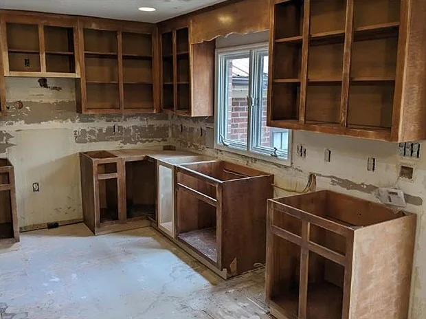 Kitchen with open wood cabinet boxes, patched walls and a bare floor
