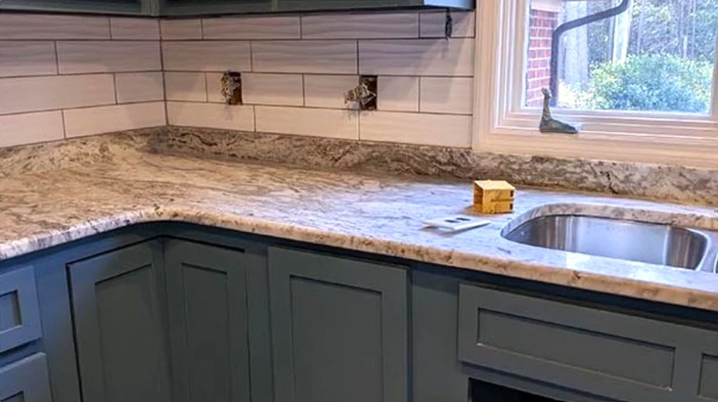 Kitchen remodel with blue-gray cabinets, a granite countertop, and a stainless sink under a window
